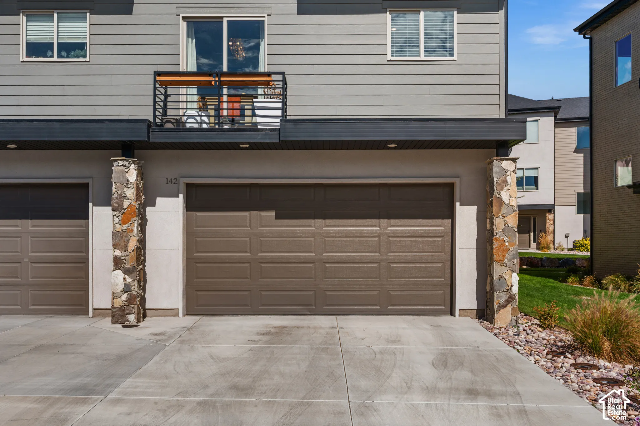 Two-car garage with a paneled door, stone-clad columns, and a concrete driveway