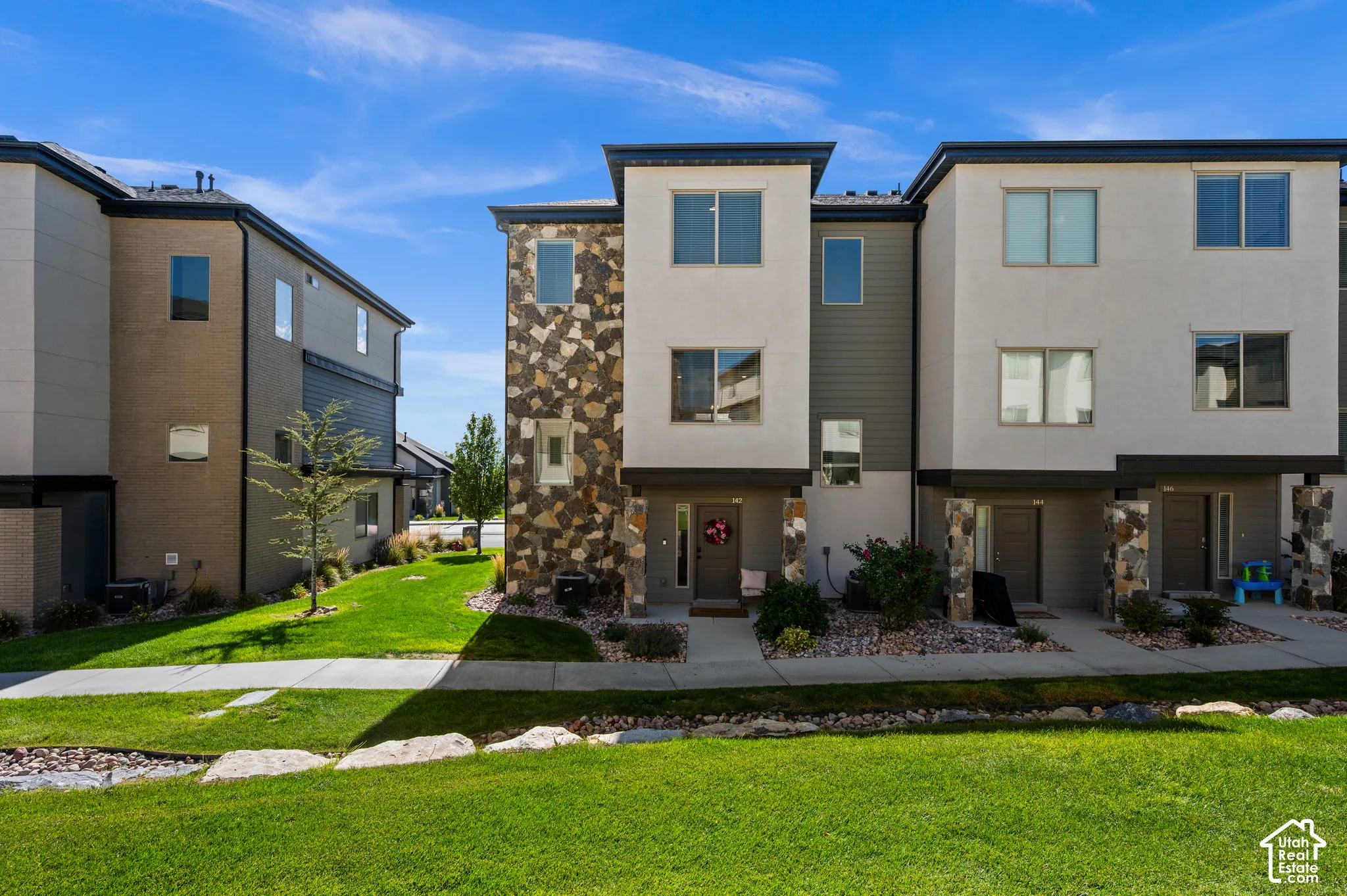 Modern multi-story facade featuring stone accents and light-toned siding