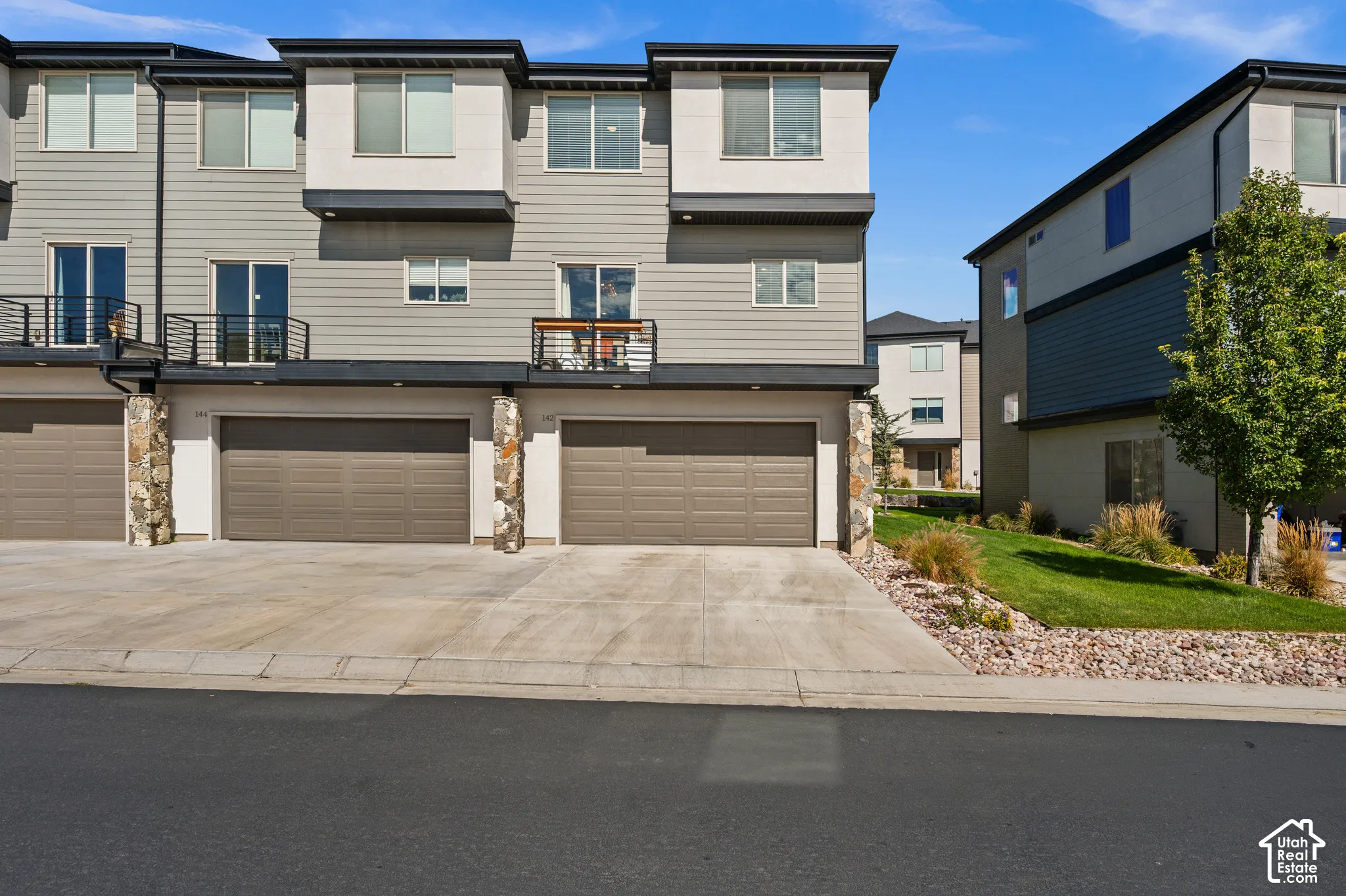 Modern townhome featuring a multi-level design, multiple balconies with black railings, and a two-car garage