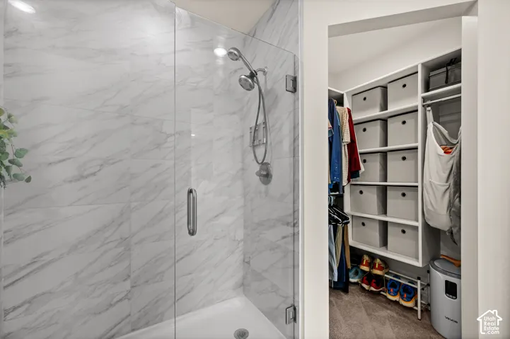 Walk-in shower with clear glass enclosure and marble-look tile surround