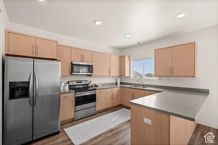 Kitchen featuring wood-finish cabinetry, stainless steel appliances, grey countertops, and recessed lighting