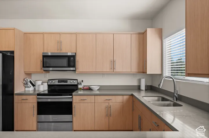 Full kitchen with light wood-finish cabinetry, stainless steel appliances, and grey countertops