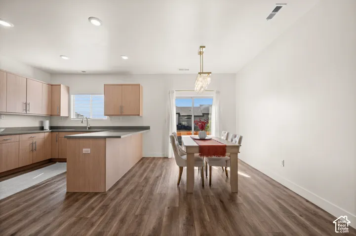 Open-concept kitchen and dining area featuring wood-finish flooring, recessed lighting, and a kitchen island with seating