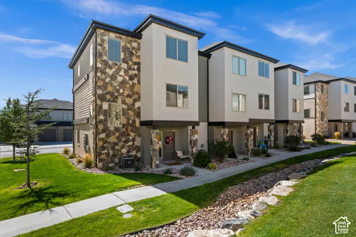 Multi-level townhome with stone facade accents, stucco exterior, and multi-pane windows