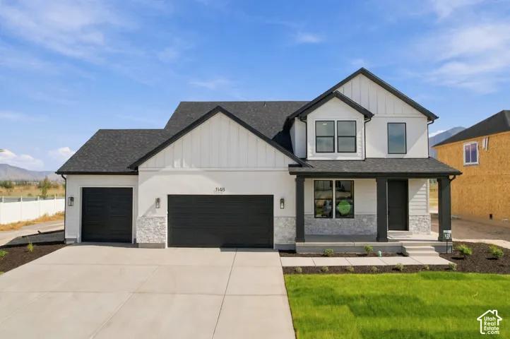 Contemporary exterior with a white and black color palette, featuring a two-car garage, covered entry, and black-framed windows