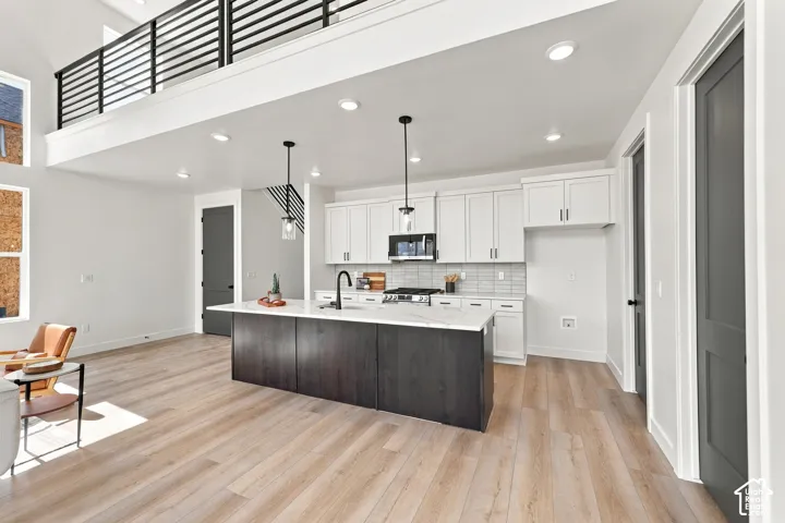 Open-concept living space featuring high ceilings, light wood-finish flooring, and a kitchen island with a light-toned countertop