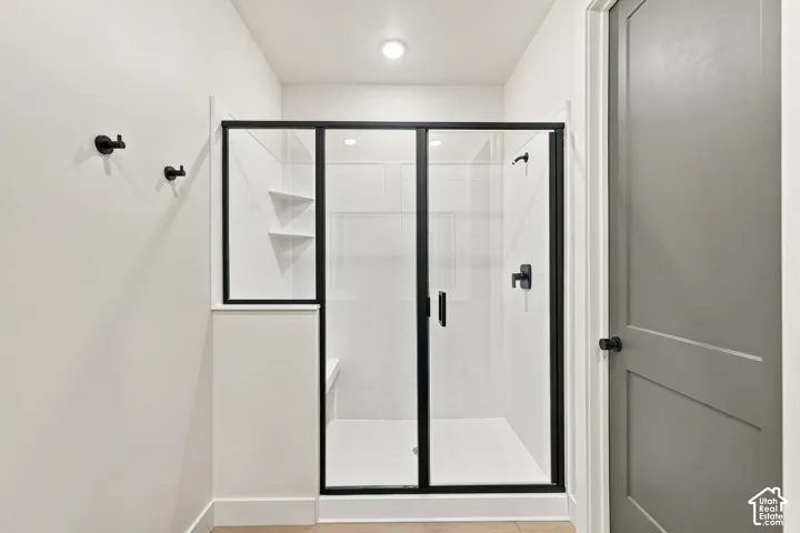 Walk-in shower with black-framed glass enclosure, white tile surround, built-in shelving, and a built-in bench