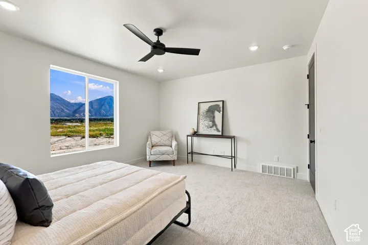 Spacious room featuring a large window with mountain scenery, a ceiling fan, recessed lighting, and light-toned carpeting