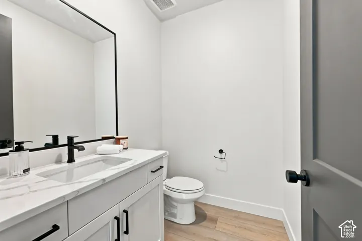 Vanity with integrated rectangular sink, stone-finish countertop, matte black hardware, and wood-finish flooring