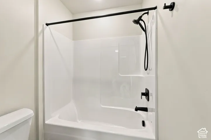 White bathtub with integrated shower, black shower rod, and matte black fixtures