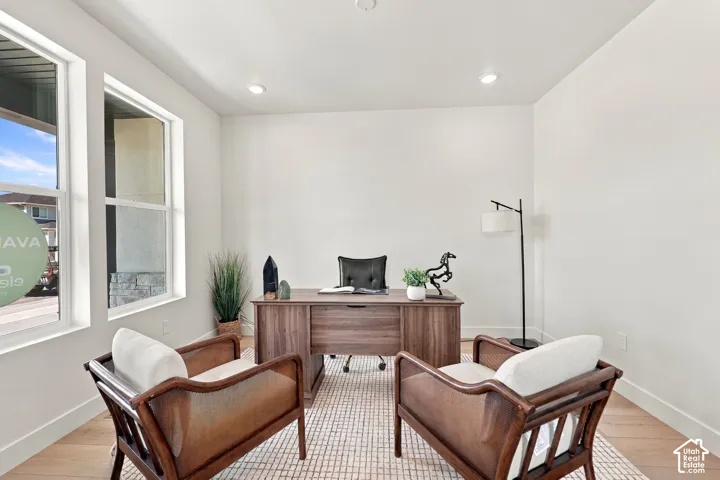 Recessed lighting illuminates this bright space featuring two large windows and wood-finish flooring