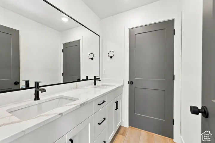 Double vanity with white cabinetry, integrated sinks, black fixtures, and a full-width framed mirror