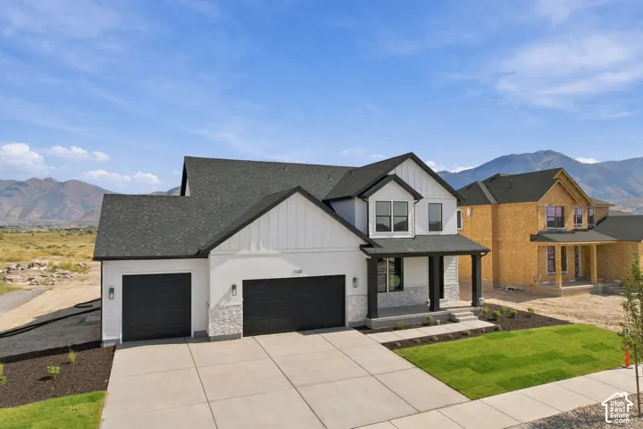 Modern two-story residence with a covered front porch, white siding, and dark trim