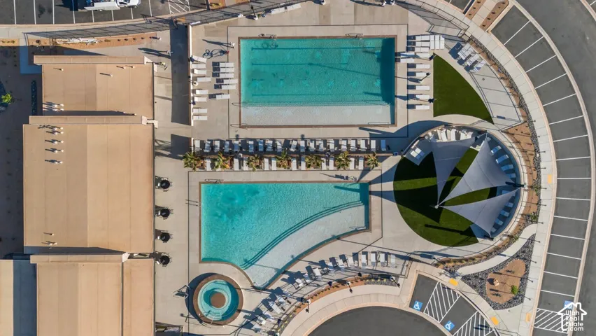 Two distinct pools, a circular spa, extensive hardscaping, and a shaded lounge area with artificial turf