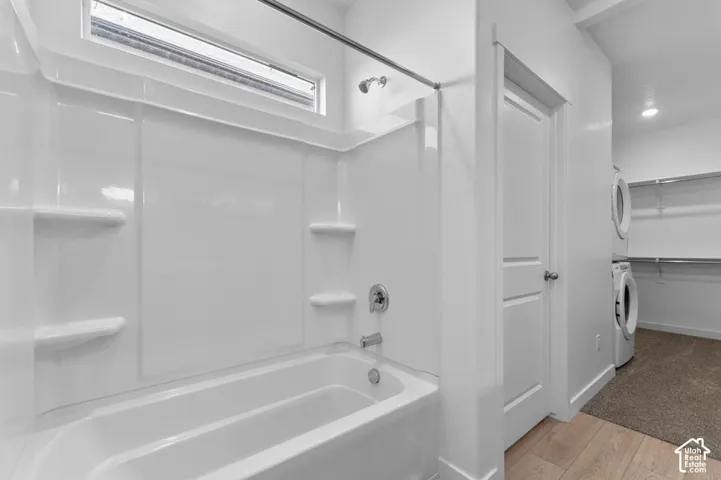White bathtub and shower combination with chrome fixtures, featuring a transom window above