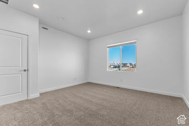 Recessed ceiling lighting, neutral carpet, white walls, and a white interior door