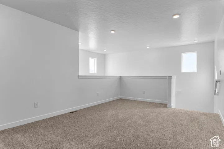 Carpeted room featuring white painted walls and recessed lighting
