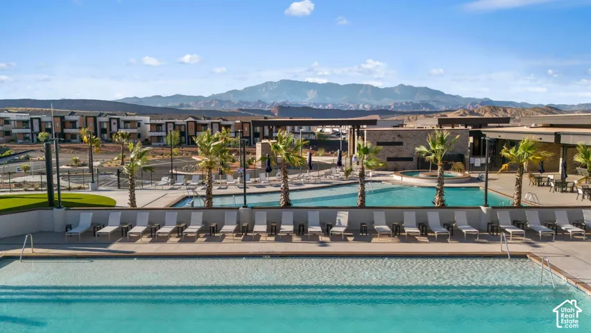 Expansive aquatic area featuring multiple pools with surrounding lounge seating, mature palm trees, and modern architecture