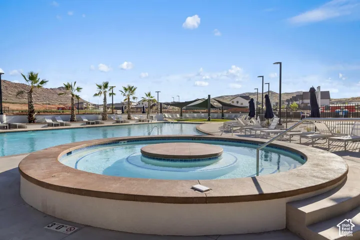Resort-style aquatic amenity featuring a circular hot tub and an expansive swimming pool