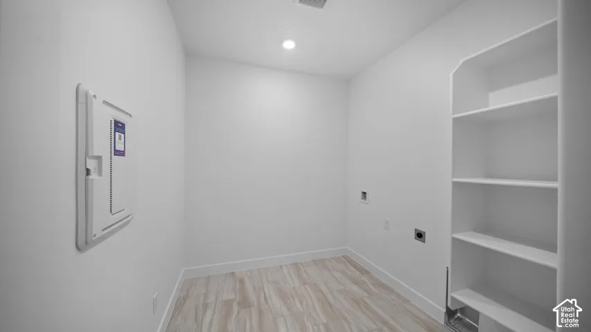 Dedicated utility space featuring built-in shelving, wood-finish flooring, and recessed lighting
