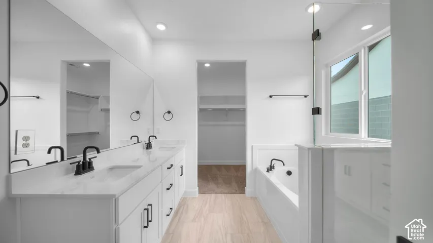 Bathroom featuring a dual vanity with white cabinetry and black hardware