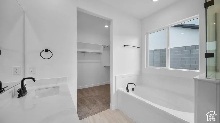 Modern bathroom featuring a built-in tub, dual-pane window, and an integrated shower enclosure