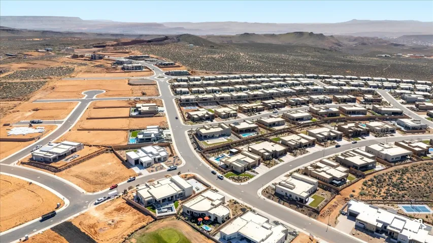 Aerial perspective of a developing residential community, featuring numerous single-story homes with flat roofs and private swimming pools