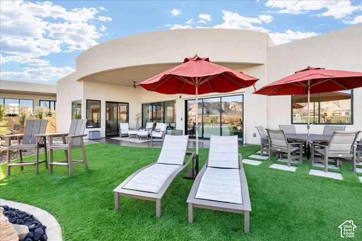 Expansive backyard featuring a manicured artificial lawn, a curved stucco exterior, and multiple sliding glass doors leading to interior spaces