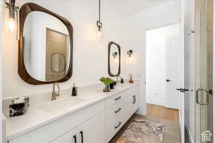 Double vanity with integrated sinks, brushed nickel fixtures, white cabinetry, and a walk-in shower with clear glass enclosure