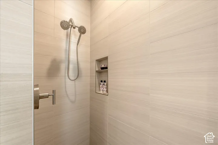Tiled shower enclosure with a recessed niche, dual shower heads, and a brushed metal faucet
