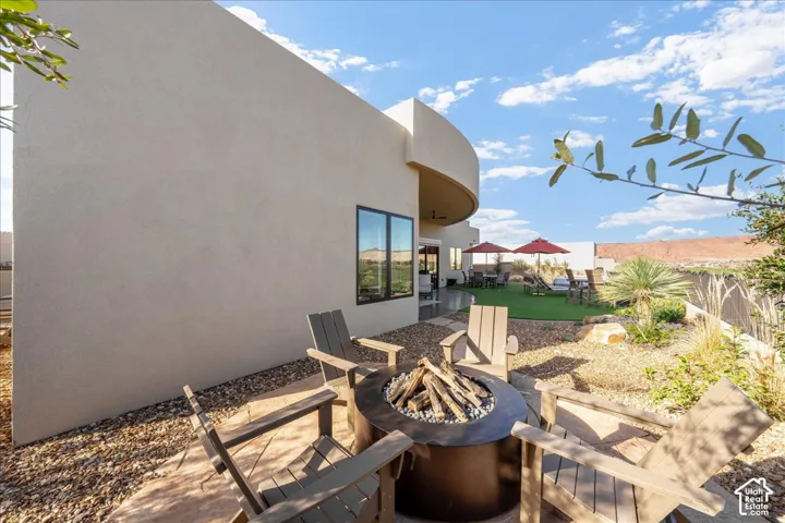 Stucco exterior with a curved architectural element, a fire pit, xeriscaping, and a compact artificial turf area