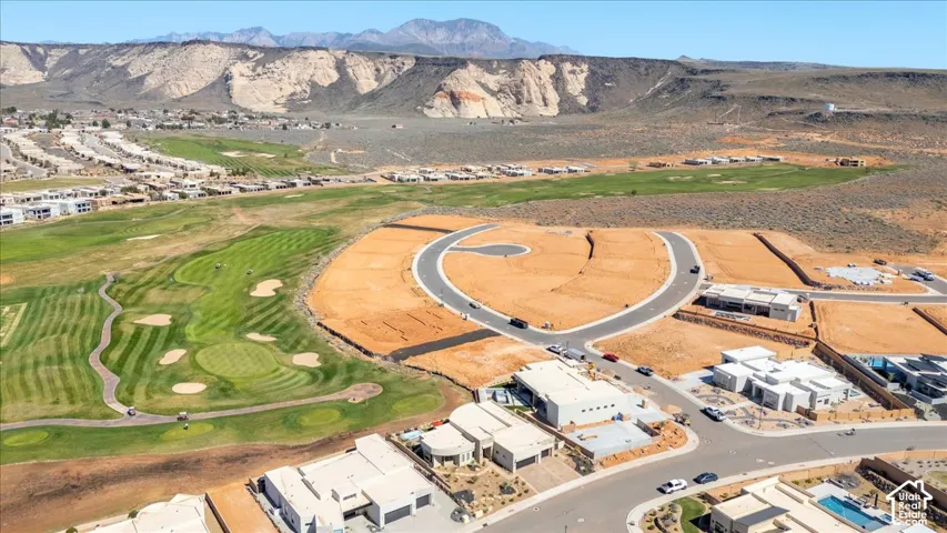 Expansive development featuring a golf course, mountain backdrop, paved roads, and modern residential structures