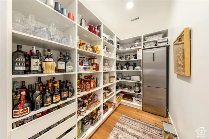Custom white built-in shelving, stainless steel refrigerator, and wood-finish flooring
