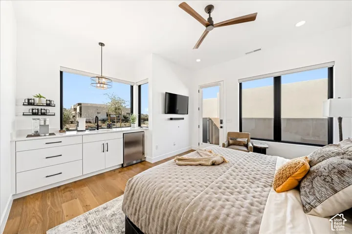 Hardwood-finish flooring, built-in wet bar with stainless steel appliances, modern ceiling fan, and large windows