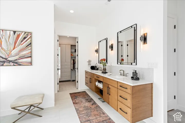Dual floating wood-finish vanities with undermount sinks, stone countertops, and rectangular framed mirrors
