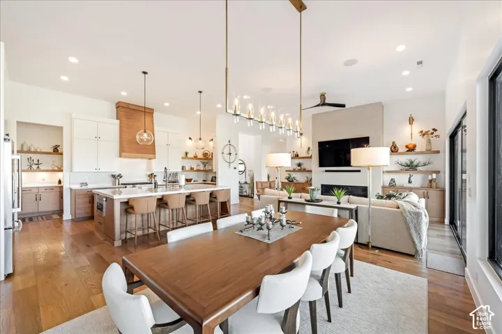 Open concept living space featuring a central kitchen island with seating, a built-in fireplace, recessed lighting, and wood-finish flooring