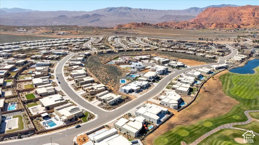 Expansive residential development with a golf course, tranquil water feature, and surrounding mountainous landscape