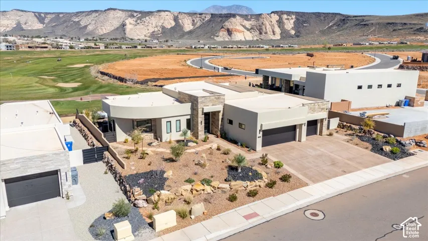 Contemporary architecture featuring a stucco exterior, stone accents, multiple garage bays, and desert landscaping
