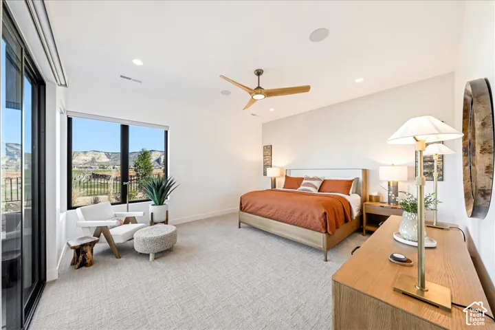 Expansive windows, light-toned carpeting, a ceiling fan, recessed lighting, and a sliding glass door to a balcony