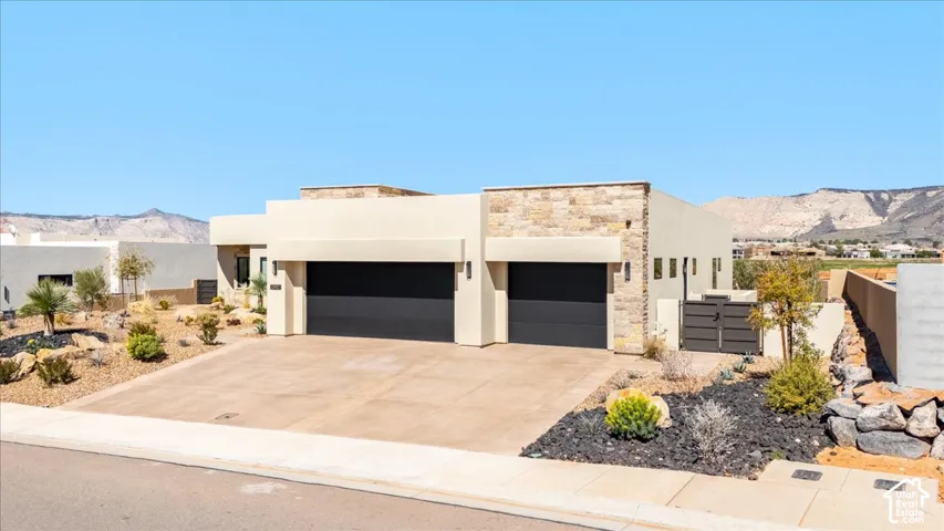 Contemporary exterior with a two-car garage, stone accents, and desert landscaping