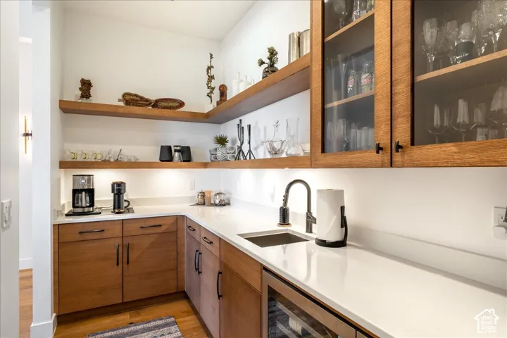 Built-in cabinetry with glass-front uppers, open shelving, integrated sink, under-cabinet lighting, and a beverage cooler