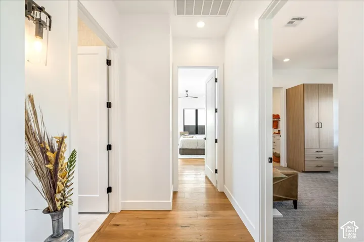 Hallway featuring wood-finish flooring, white walls, flush-mounted ceiling lights, and white paneled doors