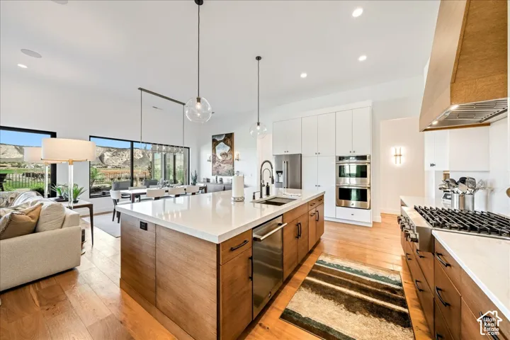 Spacious kitchen featuring an expansive central island with a solid surface countertop, stainless steel appliances, and wood-finish flooring
