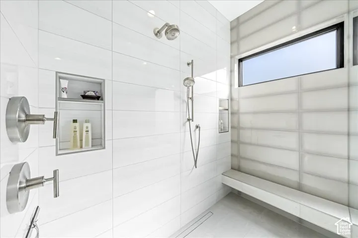 Shower featuring a built-in bench, recessed shelf, handheld showerhead, and a horizontal window