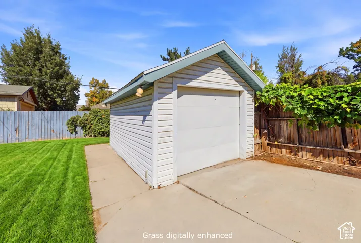 Detached garage with horizontal siding, a roll-up door, and concrete pad