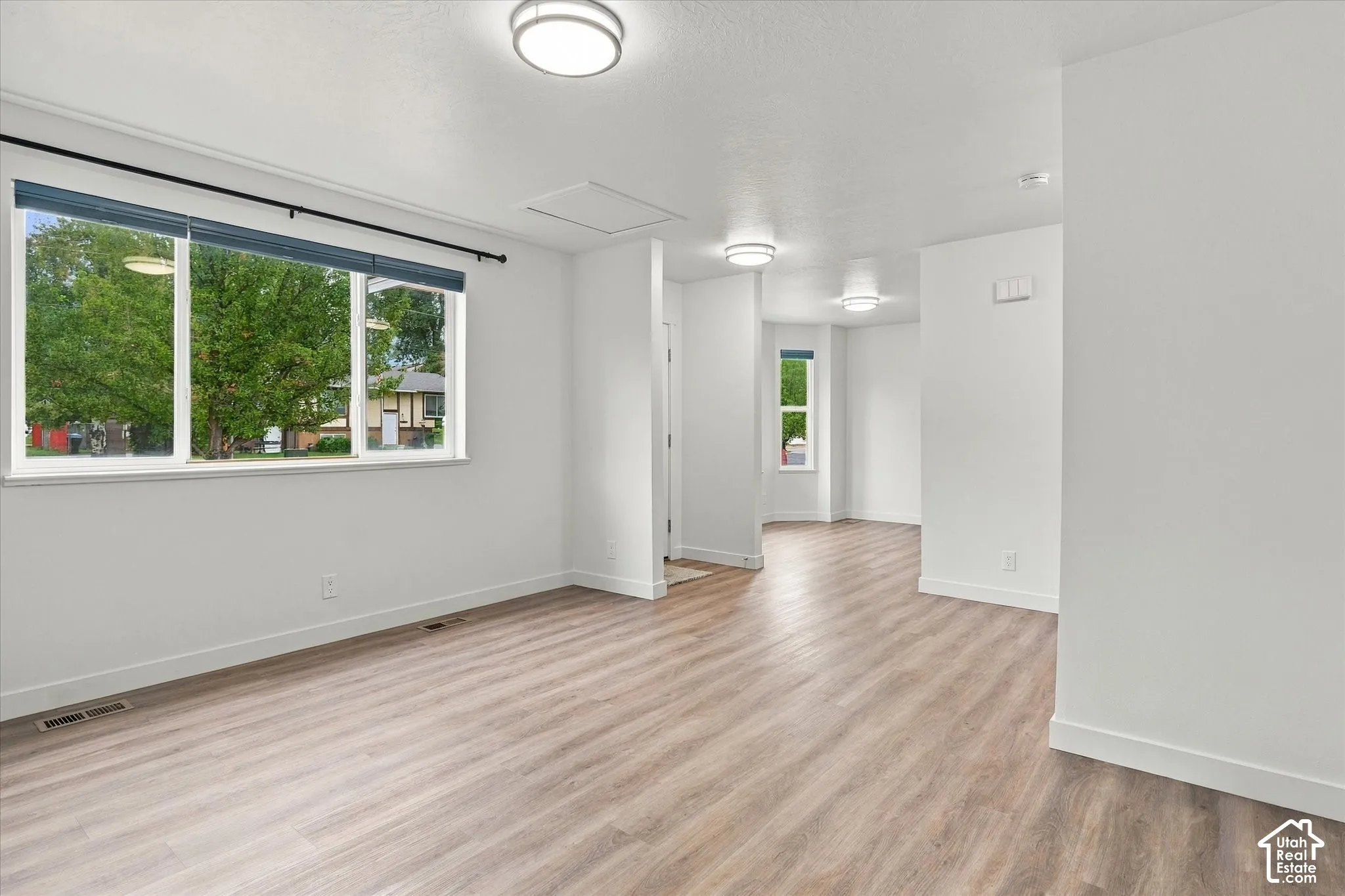 Spacious interior with wood-finish flooring, white walls, and multiple windows