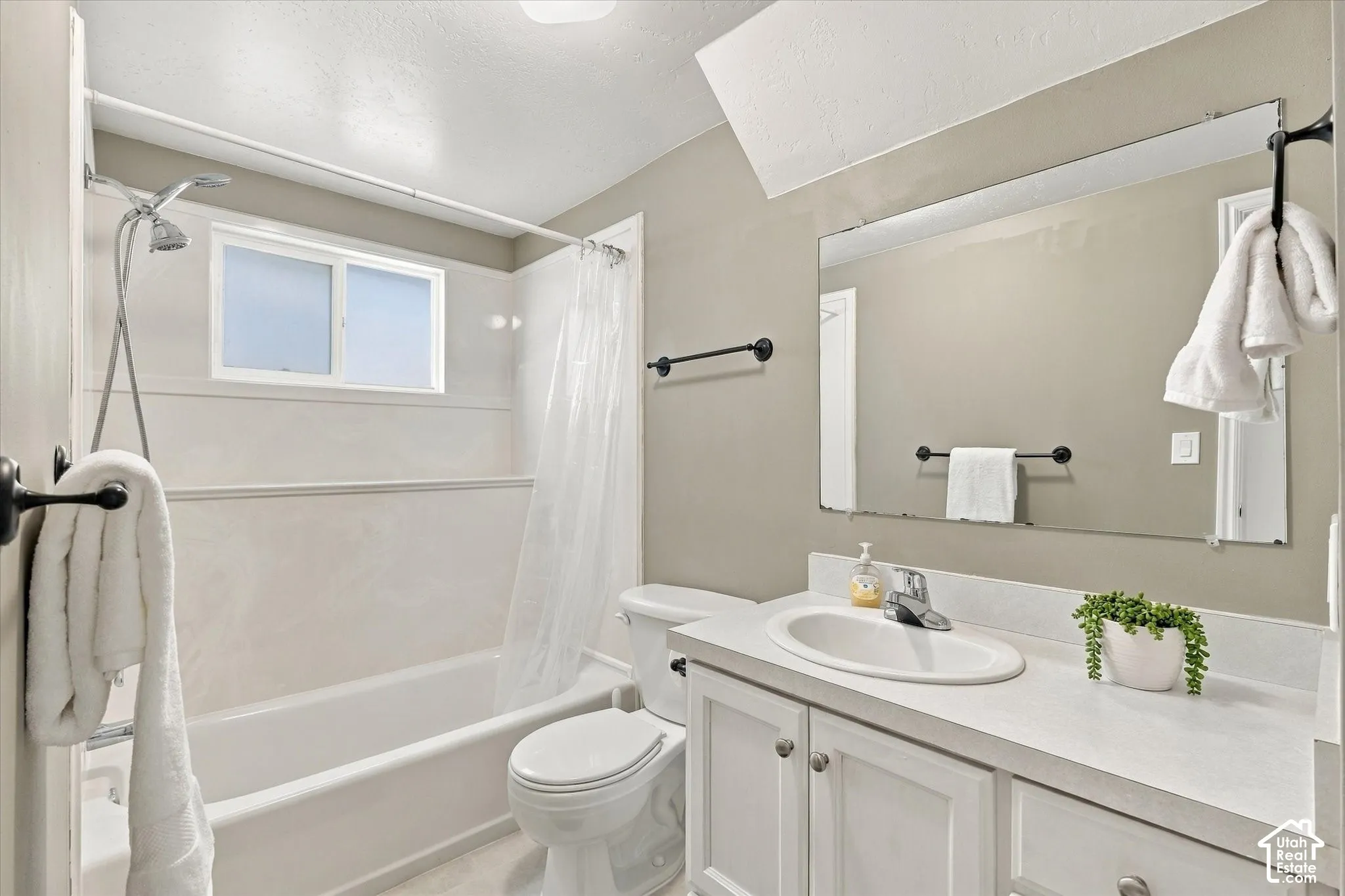 Bathroom featuring a shower-over-tub combination, vanity with integrated sink, white cabinetry, and a large wall-mounted mirror