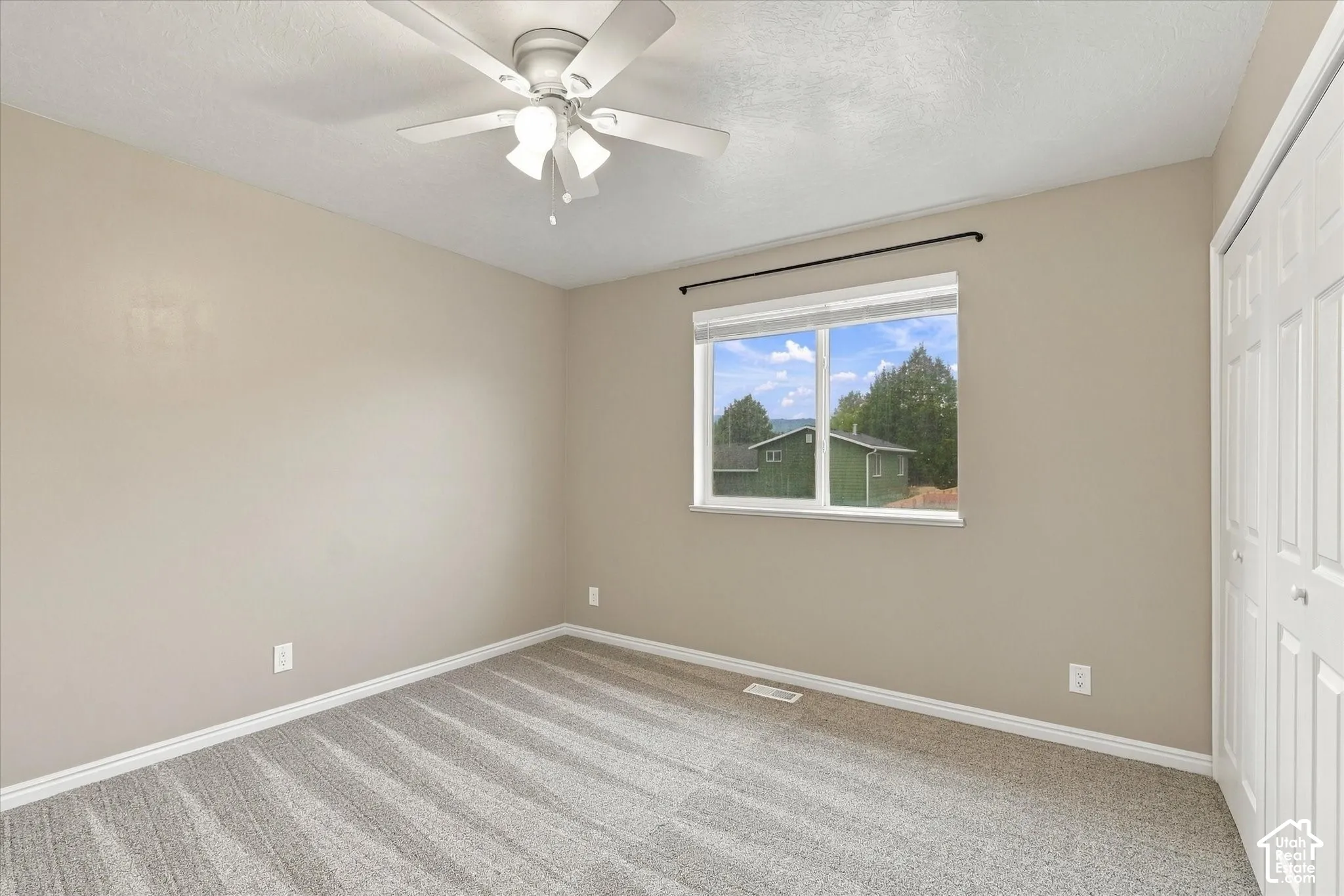 Wall-to-wall carpet flooring, a window with a black curtain rod, and a ceiling fan with integrated lighting