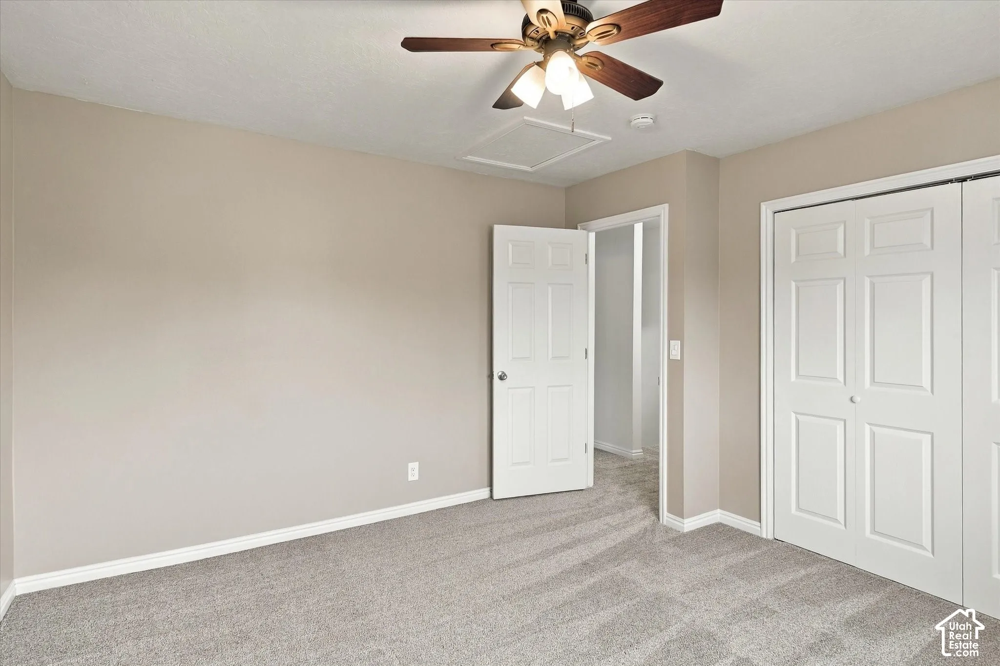 Neutral-toned walls, gray carpeting, white interior doors, and a ceiling fan with integrated lighting