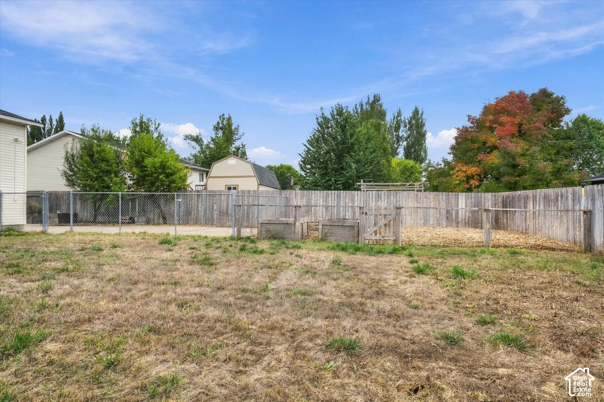 Spacious fenced yard featuring a chain-link fence, wood privacy fence, and a structured enclosure